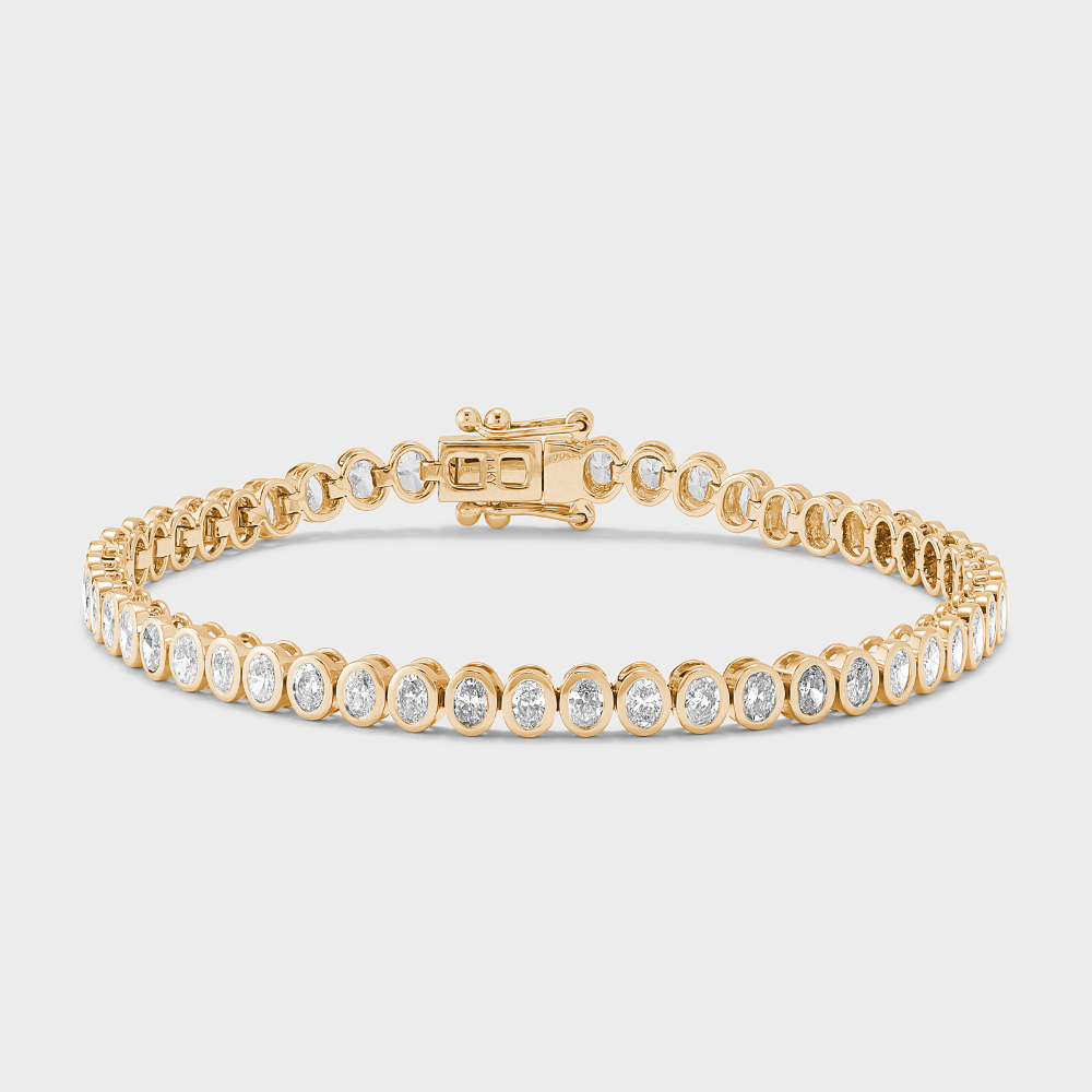 A yellow gold tennis bracelet with bezel set, oval shape natural diamonds against a white background. 