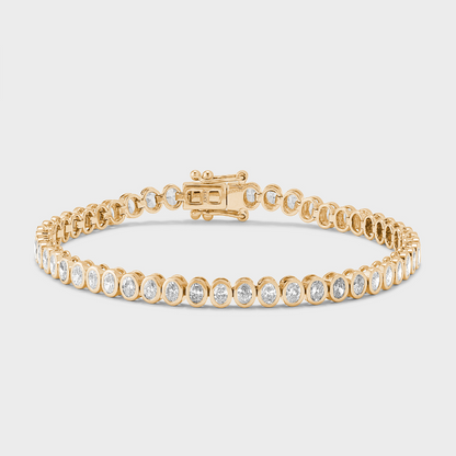 A yellow gold tennis bracelet with bezel set, oval shape natural diamonds against a white background. 