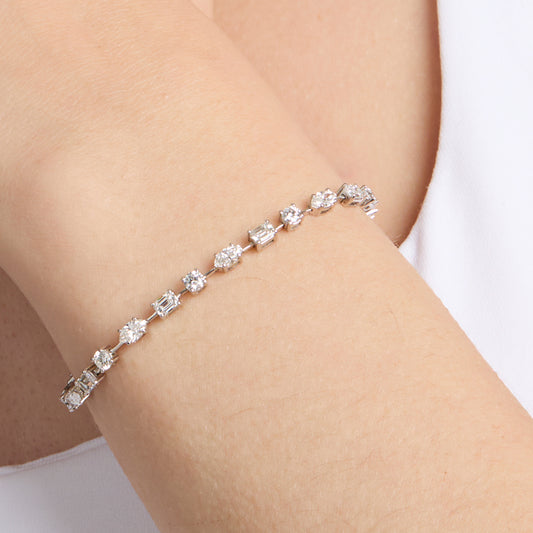 A white gold tennis bracelet with mixed fancy shaped natural diamonds on wrist. 