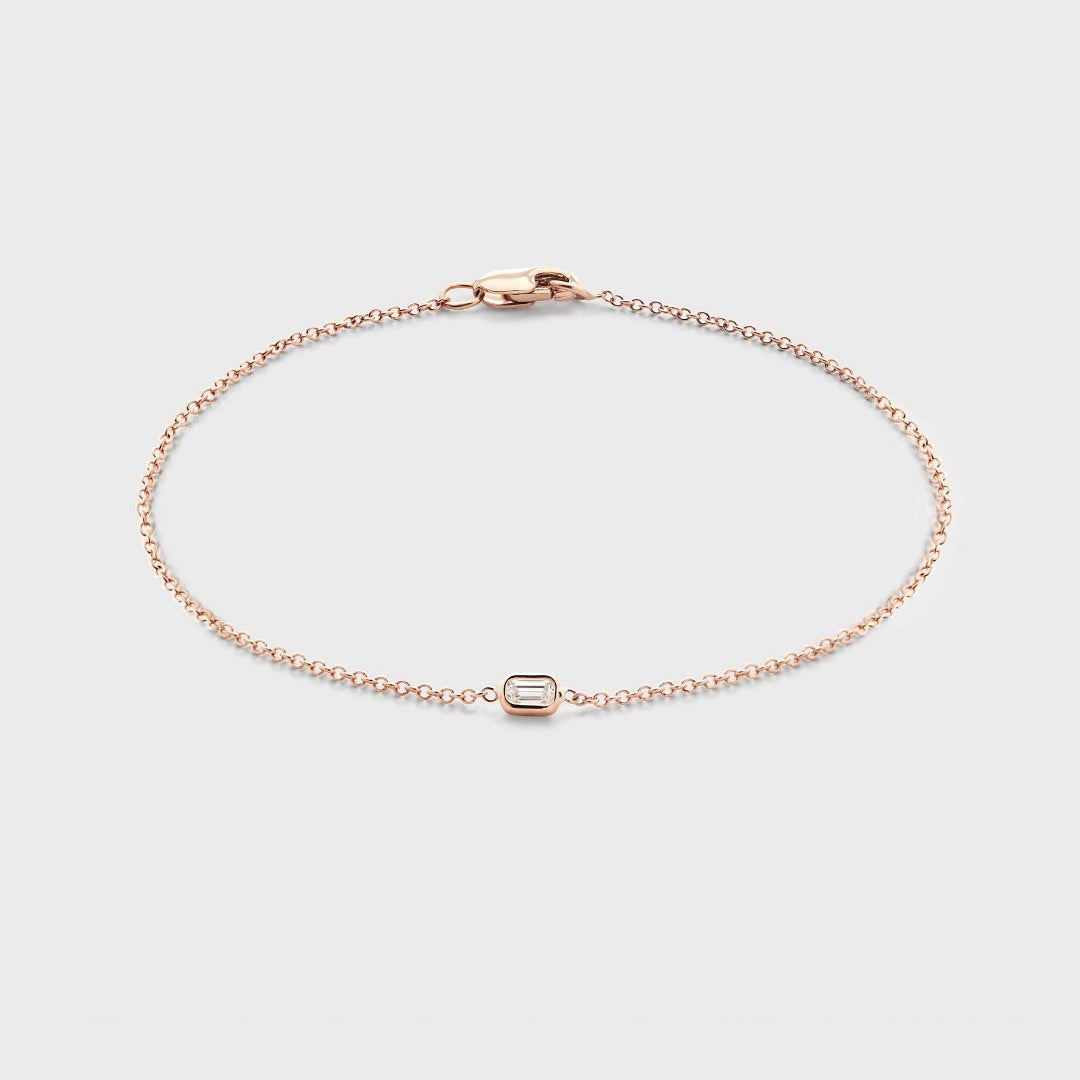 Product photo of a rose gold bracelet with a single bezel set baguette cut natural diamond. Displayed against white background. 