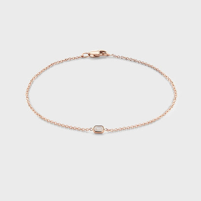 Product photo of a rose gold bracelet with a single bezel set baguette cut natural diamond. Displayed against white background. 