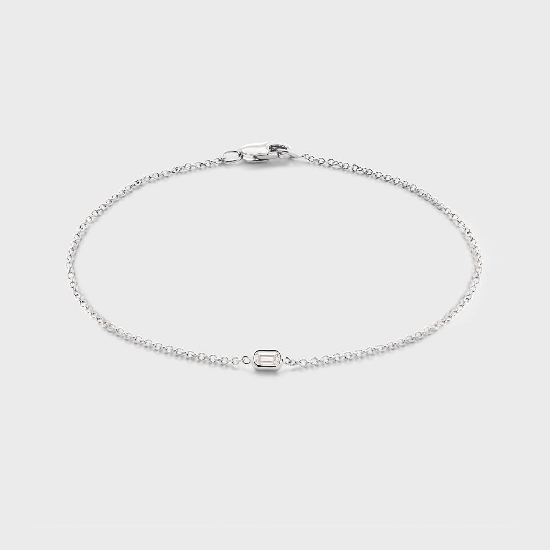 Product photo of a white gold bracelet with a single bezel set baguette cut natural diamond. Displayed against white background. 