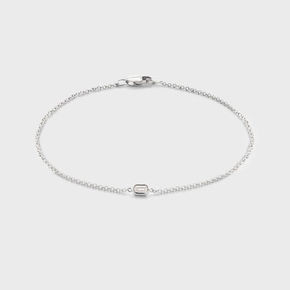Product photo of a white gold bracelet with a single bezel set baguette cut natural diamond. Displayed against white background. 