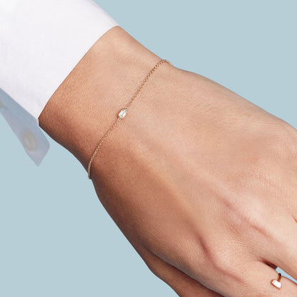 A gold bracelet with a single bezel set baguette cut natural diamond on model wrist. 
