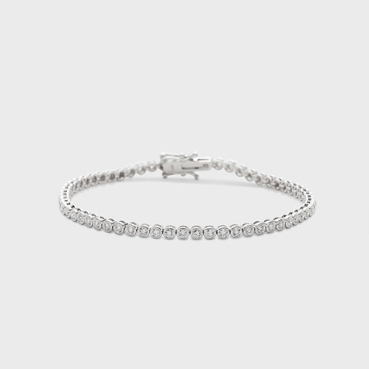 A white gold tennis bracelet with bezel set, round natural diamonds against a white background. 